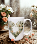 “Mug blanc décoré d’un cœur floral composé de feuilles et de fleurs pastel.”