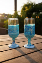 Verres artisanaux marbrés bleu et blanc dans une boîte cadeau naturelle, ambiance bohème.